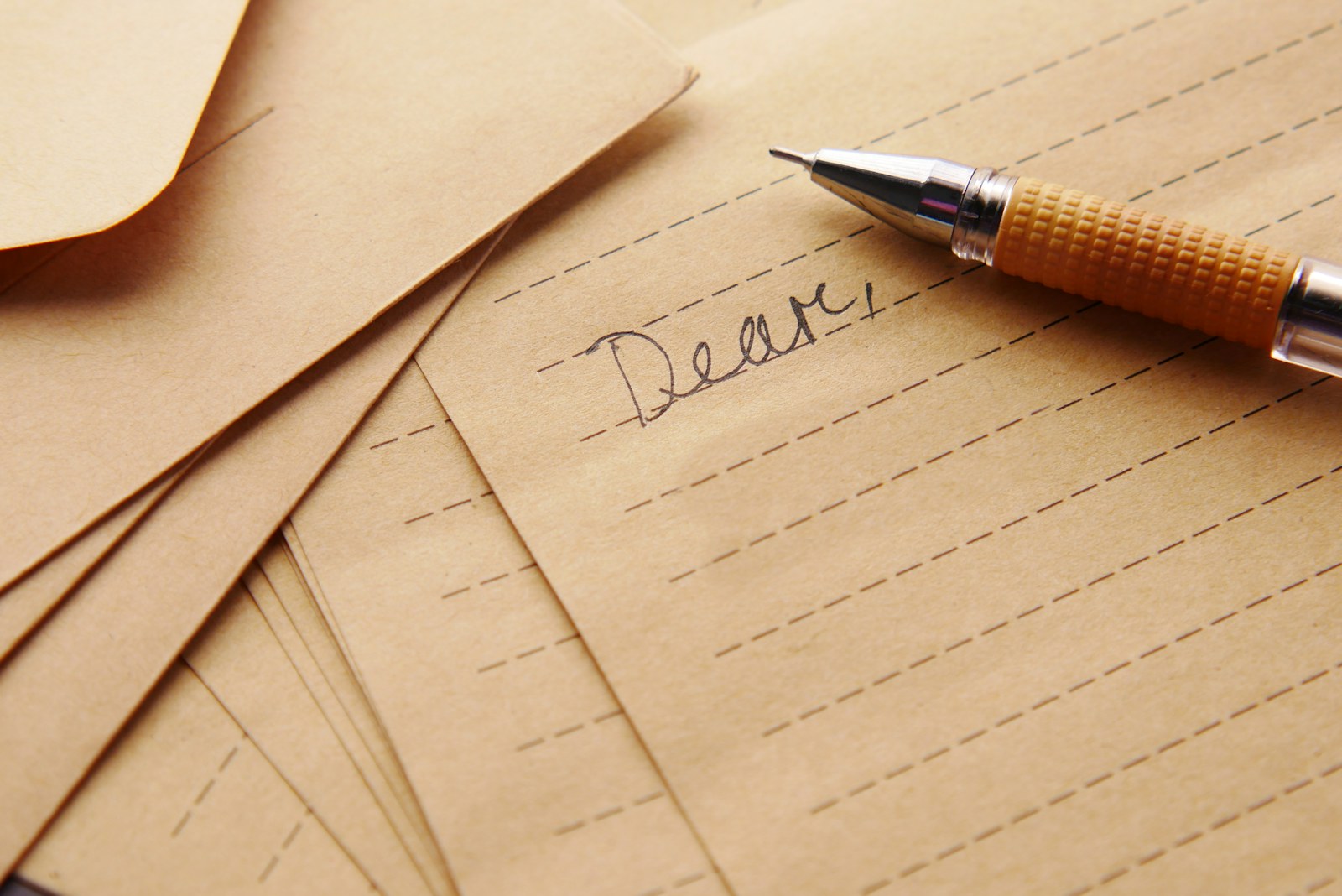 A handwritten letter beginning with Dear and a pen on the desk
